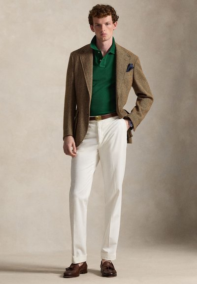 Καφέ σακάκι με σχέδιο ψαροκόκαλο, πράσινο πόλο, λευκό παντελόνι, καφέ ζώνη, σκουρόχρωμα δερμάτινα μοκασίνια. Εντυπωσιακό μαντηλάκι με πουά.