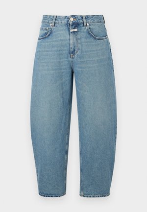 Hvit ermeløs topp med V-hals, ribbet tekstur; lyseblå, løstsittende jeans; leopardmønstrede slip-on sko.