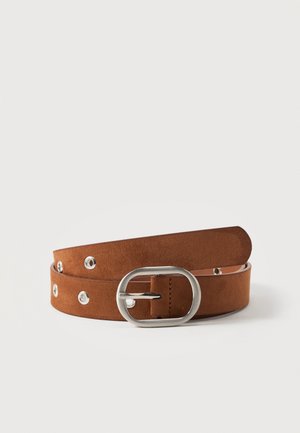 Ceinture en daim marron avec boucle ovale argentée et œillets métalliques, enroulée sur fond blanc.