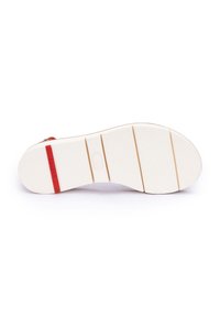 Suola della scarpa in materiale gommoso bianco, con texture antiscivolo e una striscia di accento rossa. Presenta scanalature orizzontali per una migliore aderenza.