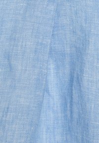 Tissu bleu clair avec un tissage fin et texturé. Le matériau semble doux avec des variations subtiles de teinte et de texture tout au long.