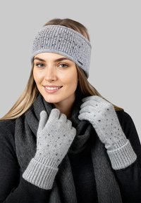 Grijze gebreide hoofdband met een geribbelde structuur en versieringen. Bijpassende vingervrije handschoenen met een zachte textuur en kleine kraaltjes. Grijze sjaal.