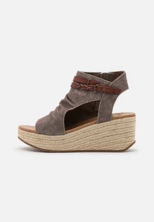Sandale compensée en tissu marron avec orteil et talon ouverts, semelle plateforme en jute tressée, et brides doubles en cuir avec boucles.