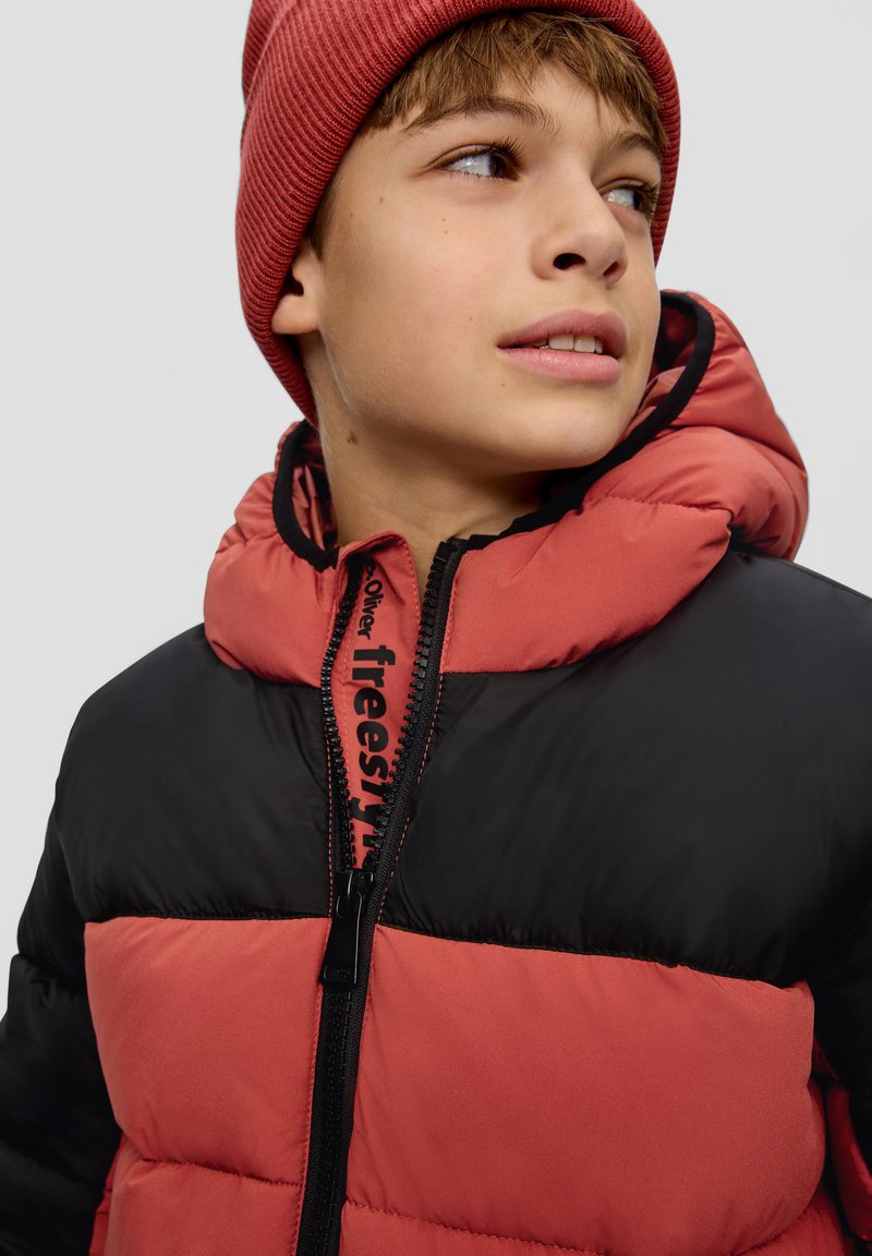 Gesteppten Jacke in Schwarz und Koralle, mit hohem Kragen, Reißverschluss und Logodetail, kombiniert mit einer gerippten Korallenmütze.