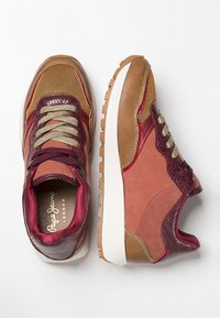 Baskets en matériaux mixtes présentant des tons bordeaux, beige et or, avec des panneaux en mesh, des accents texturés et une semelle blanche.