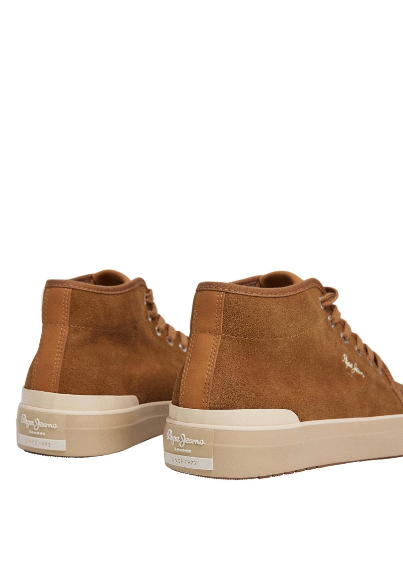 Zapatillas altas de ante marrón con suela de goma beige. Incluyen ojales de metal y un logo en el talón, con un diseño limpio y minimalista.