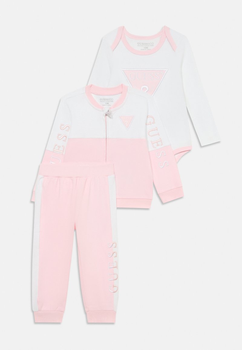 Conjunto de bebé de três peças em rosa e branco. Inclui uma jaqueta com fecho, um bodysuit de mangas compridas e umas calças com o logótipo "GUESS". Tecido suave.