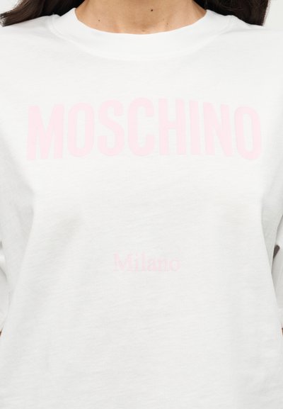 Λευκό βαμβακερό φούτερ με μεγάλο ροζ λογότυπο «MOSCHINO» στο στήθος και μικρότερο κείμενο «Milano» από κάτω, με στρογγυλή λαιμόκοψη.