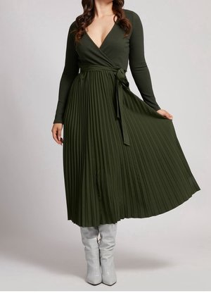 Šaty s dlouhým rukávem v olivově zelené barvě, s výstřihem do V a plisovanou sukní. Mají zavazovací pás a strukturovanou žebrovanou látku. Nošeny se šedými vysokými botami.