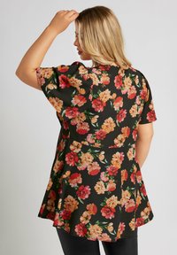 Blommig tunika i svart med korta ärmar, prydd med stora rosor i nyanser av rosa, orange och gult. Flödande design med en utsvängd form.