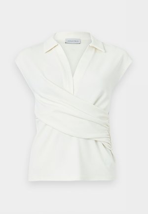 Fehér ujjatlan blúz gallérral, V-nyakkivágással és átfedő elülső részlettel, enyhén összegyűrve az egyik oldalon.