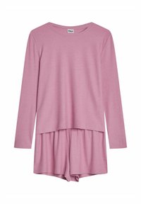 Jasnoróżowa bluzka z długim rękawem, o prążkowanej fakturze i luźnym kroju, zestawiona z dopasowanymi szortami z plisowaniem w pasie.