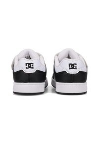 Schwarz-weiße DC-Sneaker mit einer Oberseite aus Leder, dicken Sohlen und gepolsterten Knöchelkragen sowie einem Logodetail an der Ferse.