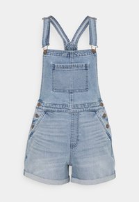 Vaaleansiniset farkkuhaalarit, joissa on säädettävät hihnat, etutasku ja kolme pronssista nappikoristetta sivuilla. Sisältää lyhyet, käärityt lahkeet.