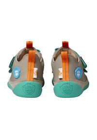 Kinder Schuhe in Beige mit türkisfarbenen Sohlen. Merkmale sind ein orangefarbener Fersenakzent, ein blauer Logo-Patch und ein strukturiertes, leichtes Design. Mit Klettverschluss.
