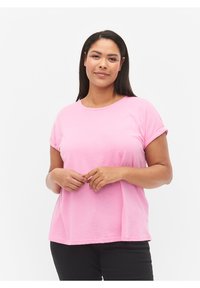 Camiseta de algodón rosa con mangas cortas enrolladas y escote redondo, que presenta un ajuste relajado y una textura suave. Se lleva con pantalones negros.