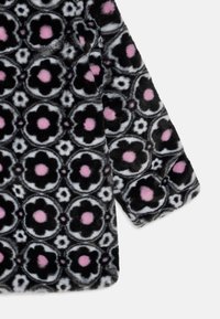 Svart och grått faux fur-tyg med ett blommönster som har rosa accenter, mjuk textur och rundade former i en mysig design.