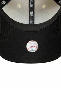 Gorra de béisbol negra con visera plana, que presenta una etiqueta reflectante de la MLB en la parte frontal. El revestimiento interior es gris claro y cuenta con agujeros de ventilación.