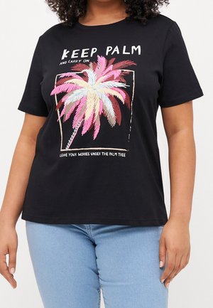 Frau trägt ein schwarzes T-Shirt mit einer bunten Palmen-Grafik und dem Text "Keep Palm and Carry On" und "Leave Your Worries Under the Palm Tree."