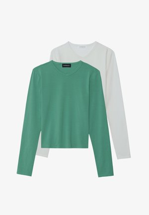 Long-sleeve v-neck shirts in green and white. Green shirt has a solid texture, while white shirt is slightly longer and layered underneath.