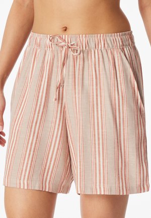 Blick von der Taille abwärts auf eine Person, die hellbeige Shorts mit vertikalen rosa und weißen Streifen und vorne gebundener Kordel trägt.