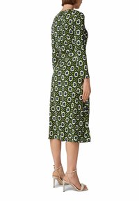 Groene gestreepte jurk met lange mouwen, knielang, met een bloemenpatroon in blauw en wit. Draag nauwelijks met beige sleehakken.