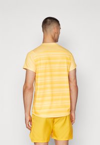 Gulstripete kortermet skjorte med rund hals, laget av lett stoff, kombinert med matchende gule shorts.