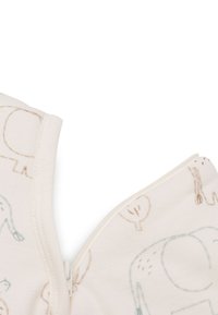 Gros plan sur un vêtement pour bébé beige avec une fermeture éclair et des illustrations d'animaux et d'arbres en marron clair et bleu sur le tissu.