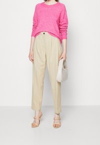 Fuchsia stickad tröja, beige högmidjade byxor, ljusbeige handväska och sandfärgade klacksandaler, med en avslappnad passform och texturerad tyg.