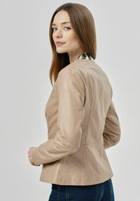 Beżowa skórzana kurtka o dopasowanym kroju, z szwami na ramionach i podszytym kołnierzem w zielono-białe paski.