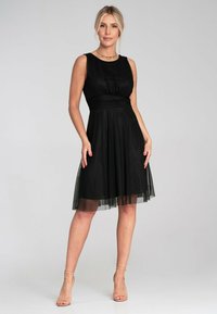 Schwarzes ärmelloses Kleid mit einem taillierten Oberteil, gerafftem Stoff an der Taille und einem knielangen Rock mit einem transparenten Überzug.