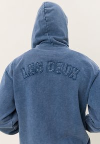 Hoody in vervaagd blauwe katoen, met geborduurde "LES DEUX" tekst op de achterkant, in een relaxte pasvorm en met geribde manchetten.