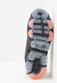 Nike Air Max-sula, svart med transparenta sektioner. Har orange detaljer, rundade kuddar och en texturerad yta för grepp.