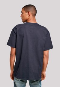 Dark navy short-sleeve t-shirt in cotton with a relaxed fit. Features a round neckline and smooth texture, worn with light blue denim jeans.