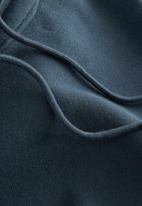 Mjuk marinblåtyg med en slät yta, med flödande veck och subtila kurvor. Inga distinkta mönster eller ytterligare detaljer synliga.