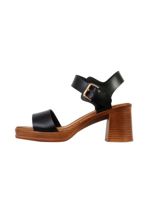 Sandale en cuir noir avec talon bloc en bois, bride à la cheville avec boucle dorée et design à bout ouvert sur fond blanc.