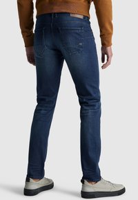 Mörkblå denimjeans med slim fit, med fem fickor, subtil blekning och en läderlabel i midjan. I kombination med ljusa sneakers.