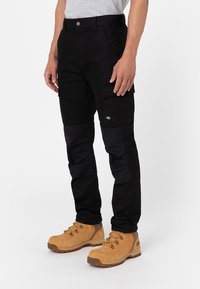Black cargo pants with a structured fit, featuring side pockets, a textured fabric, and a contrasting panel design on the legs.