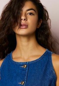 Farmerkék ruha kör alakú nyakkivágással, aranyszínű szív alakú gombokkal és sötétkék mosással. A textúra simának tűnik, látható varrással.