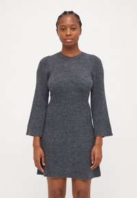 Robe en tricot côtelé gris avec un corsage ajusté, des manches longues évasées et un col rond, présentant des lignes texturées et une encolure légèrement évasée.