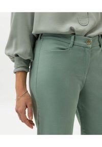 Mintgröna skräddarsydda byxor i mjukt tyg, med knappstängning, framfickor och slät yta. Designade för en åtsittande look.