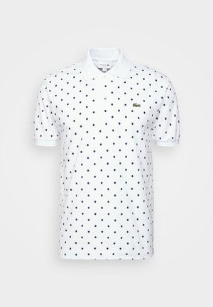 Weißes kurzärmeliges Poloshirt mit marineblauen Polka-Dots, einem Kragen, zwei Knöpfen und einem kleinen grünen Krokodillogo auf der Brust.