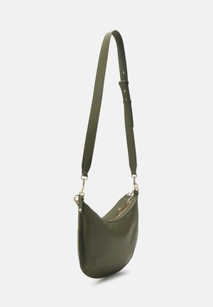 Olijfgroene leren crossbodytas met verstelbare riem, goudkleurige hardware en ritssluiting bovenaan, afgebeeld tegen een effen achtergrond.