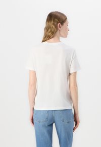 T-shirt bianca in cotone con maniche corte, scollatura rotonda e vestibilità comoda, abbinata a jeans in denim blu chiaro. Design minimalista e semplice.