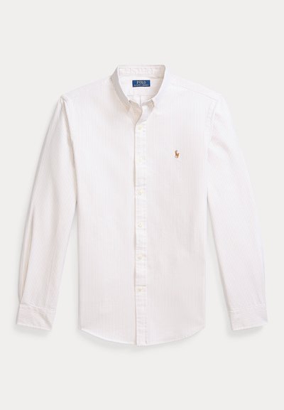 Camisa branca de botões com riscas claras, mangas compridas, gola pontiaguda e logótipo bordado no peito. Material de algodão, textura suave.