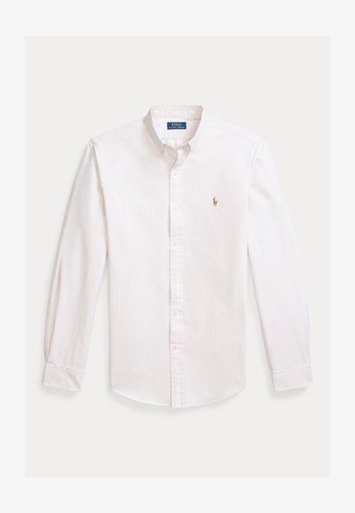 Camisa branca de botões com riscas claras, mangas compridas, gola pontiaguda e logótipo bordado no peito. Material de algodão, textura suave.