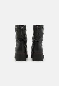 Botine negre din piele cu fermoare laterale, având o suprafață texturată, toc pătrat și detalii subtile de cusătură pe toc și fermoar.