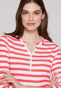 Red and white striped long-sleeve top with a V-neck and three-button front. Fabric appears ribbed with smooth texture.