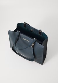 Temno modra Valentino usnjena torbica z teksturirano površino, dvema ročajema, odprtim vrhom s pritrdilnim zapiranjem in zlatimi kovinskimi dodatki.