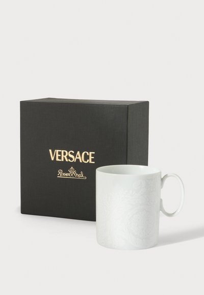 Tasse en céramique blanche avec un motif en relief subtil à côté d'une boîte noire présentant les logos dorés de Versace et Rosenthal.